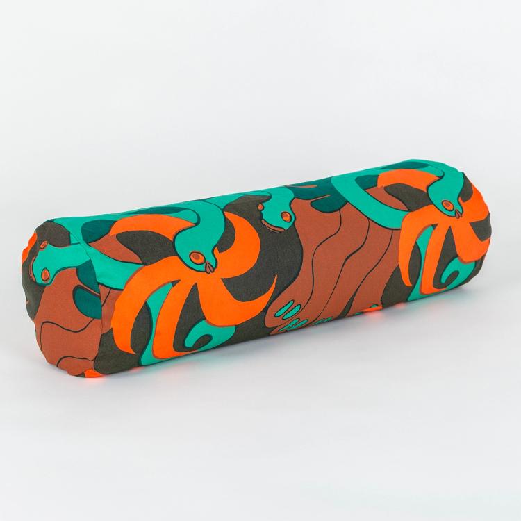 A long cylindrical pillow positioned at a 45-degree angle toward the camera. The fabric making up the pillow features a repeating textile pattern with stylized green snakes intertwined with abstract brown shapes and bright orange spirals on a dark brown background.