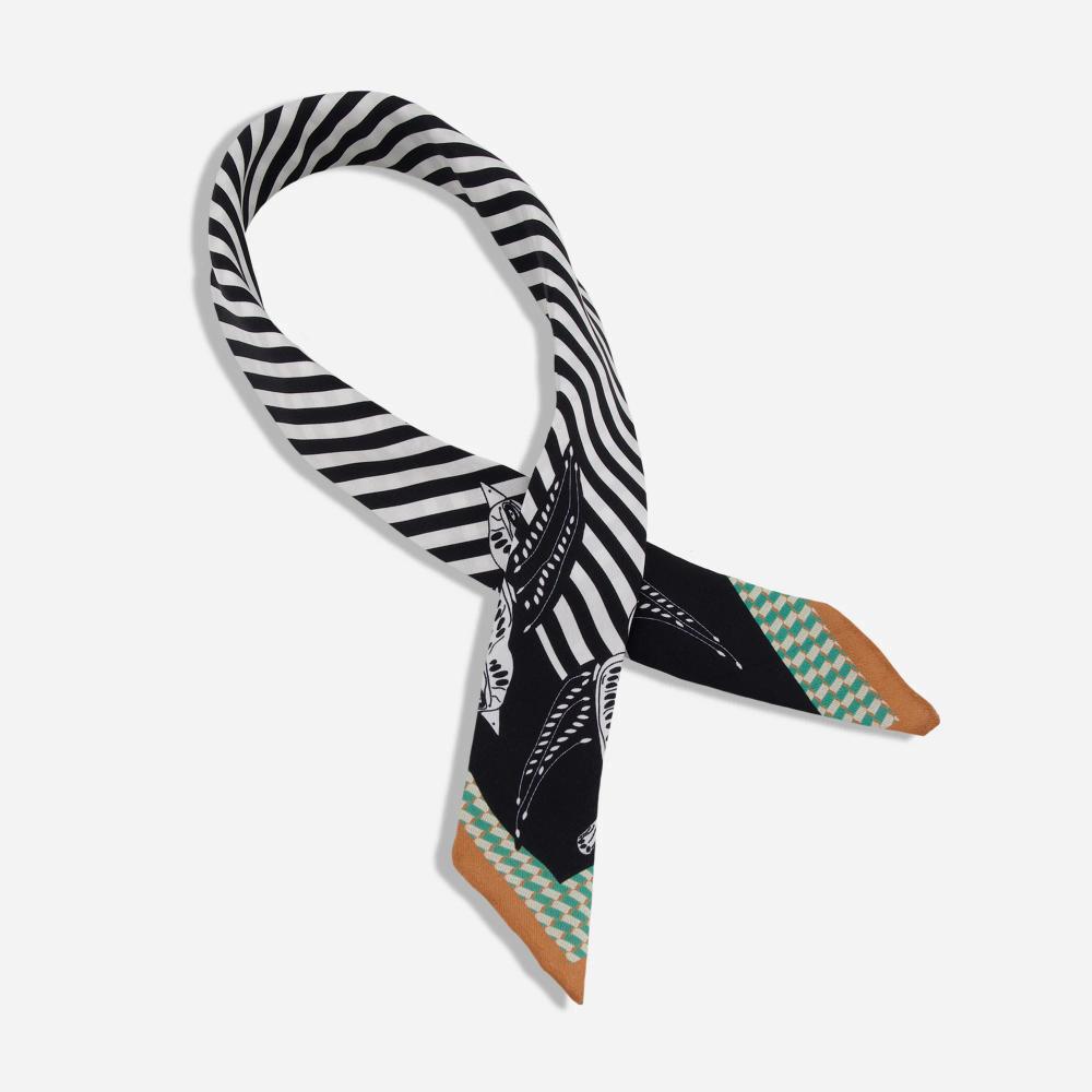 A scarf wrapped in a loop so as to allow space for a wearer's neck. Each end features stripes of tan, followed by a houndstooth pattern of green and cream, followed by a broader black border over which illustrated birds are printed. Around the neck loop are black and white stripes.