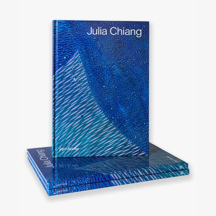 A book titled "Julia Chiang," featuring a dynamic abstract design with sweeping diagonal strokes in shades of blue, teal, and purple stacked on top of two more of the same books showing a thin thickness.