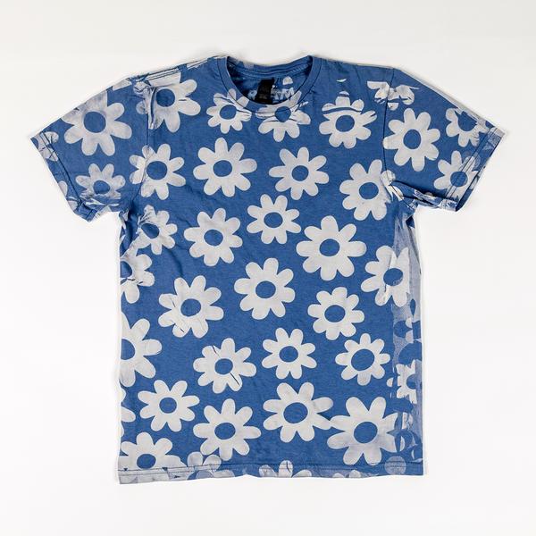 A sky blue t-shirt with a series of white cartoon-like daisy shapes printed across it. 