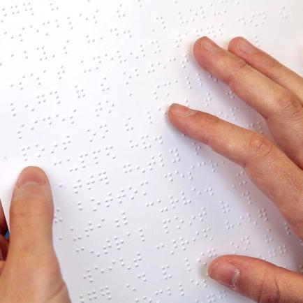An image of a person running their fingers over the braille on the surface of the artwork.