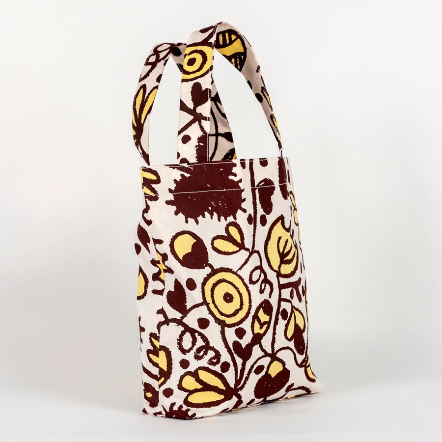 A tall, rectangular tote bag made of fabric yardage consisting of brown and yellow floral motifs.