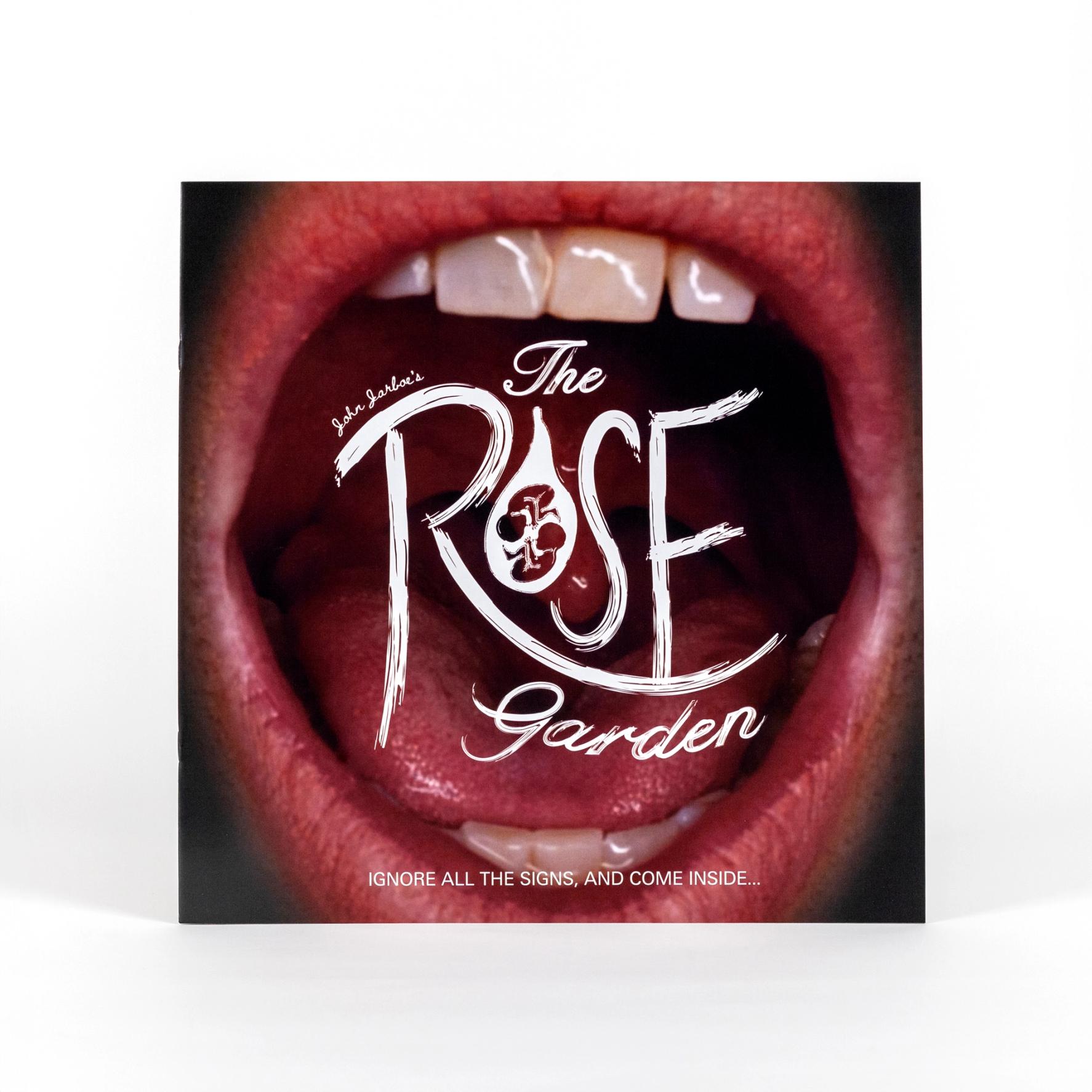 A cover of a square book. The image on the book is a close-up photo of a mouth open wide. There is text overlaying the open mouth that reads "John Jarboe's The Rose Garden IGNORE ALL THE SIGNS, AND COME INSIDE..."