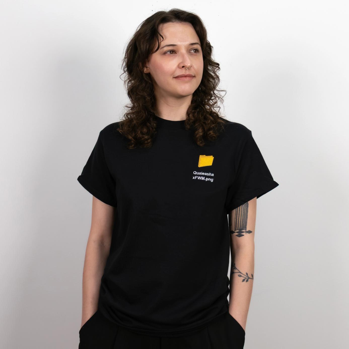 A photo of a model wearing a black t-shirt with a 1.5 inch yellow computer desktop folder embroidered on the upper left side of the shirt. Below the folder reads "Qualeasha x FWM.png" in white embroidery thread.