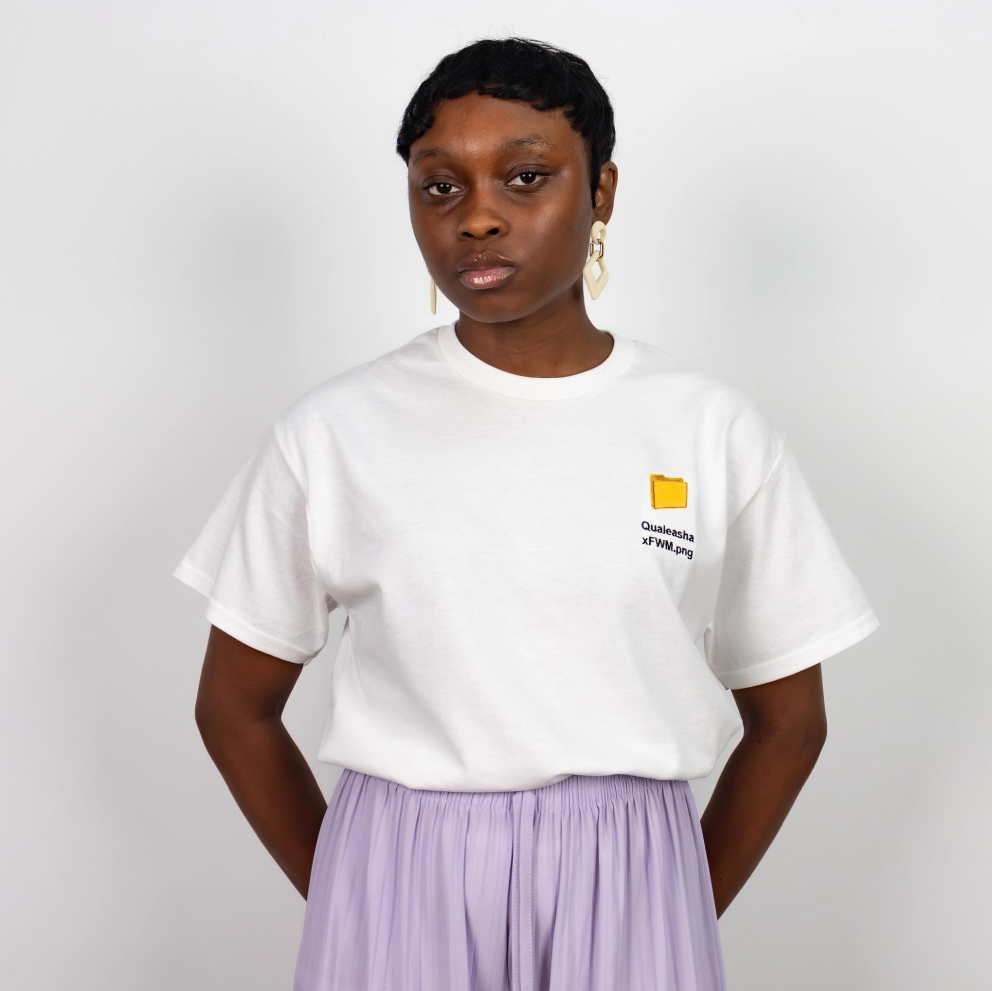 A photo of a model wearing a white t-shirt with a 1.5 inch yellow computer desktop folder embroidered on the upper left side of the shirt. Below the folder reads "Qualeasha x FWM.png" in black embroidery thread.