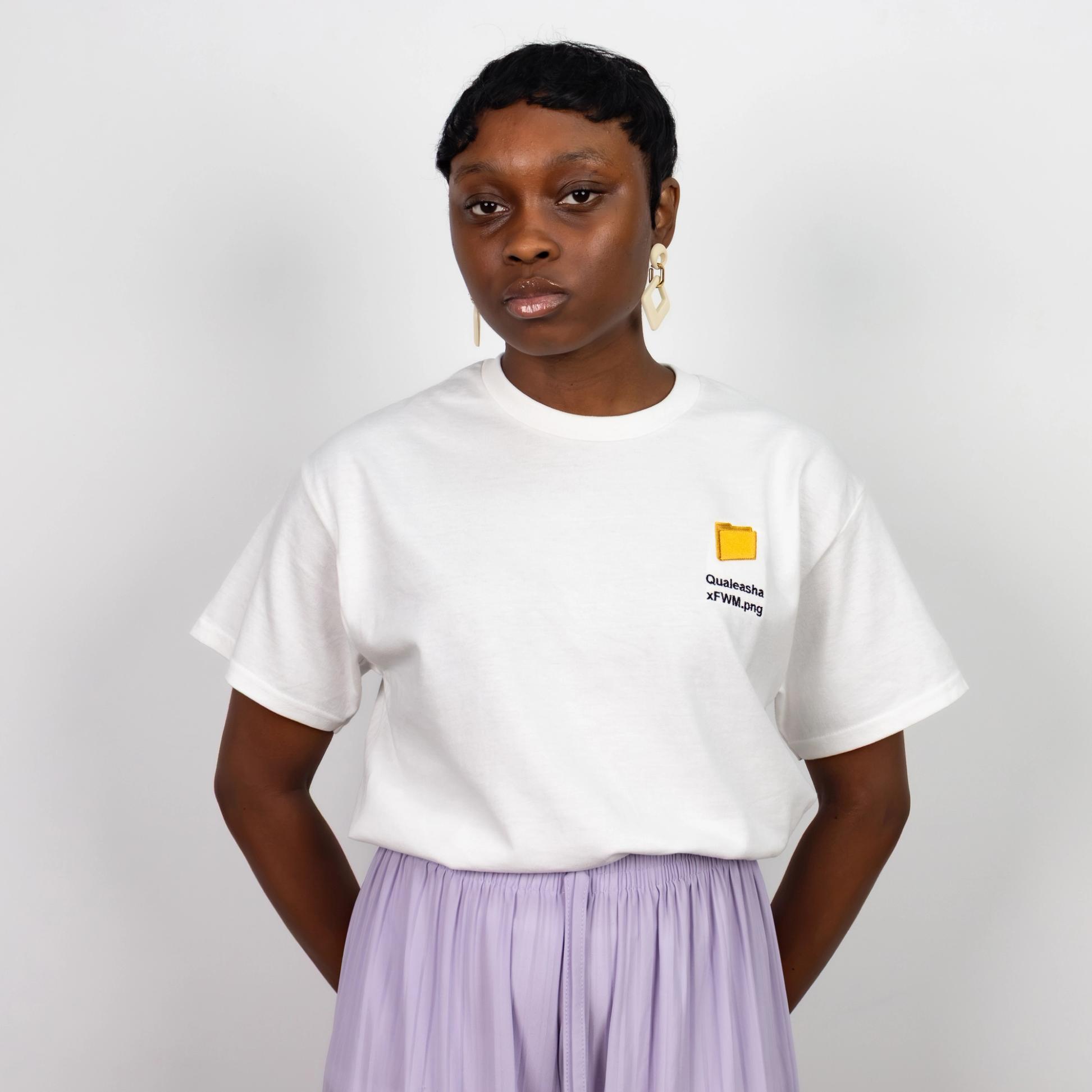 A photo of a model wearing a white t-shirt with a 1.5 inch yellow computer desktop folder embroidered on the upper left side of the shirt. Below the folder reads "Qualeasha x FWM.png" in black embroidery thread.