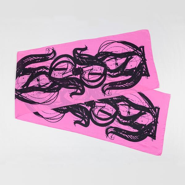 A silk scarf is folded and split diagonally against a white ground. This one is pink and features bold, painterly gestures with ink drips and splatters that follow the curving motion of a brush.