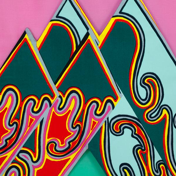 A close up of a colorful textile wall hanging with overlapping diamond-shaped panels in a mirrored repeat pattern. Inside there is a sheer green diamond. The overlapping diamonds are framed by a sheer pink fabric background.