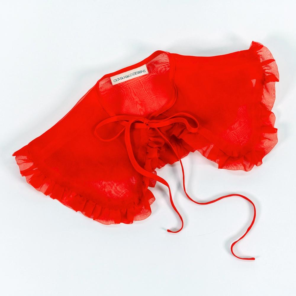 A red silk organza removable collar is sitting against a white background. The collar has a rounded edge and ruffle going all the way around. The tie is silk and ties in a bow.
