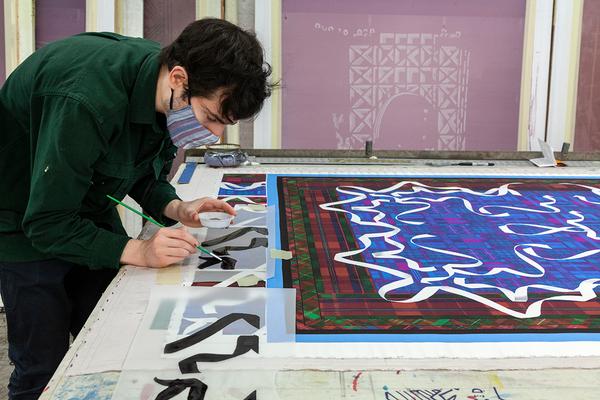 A photograph of an artist hand-painting over a table. A detail of Samara Golden's blanket in progress appears at the right of the image.