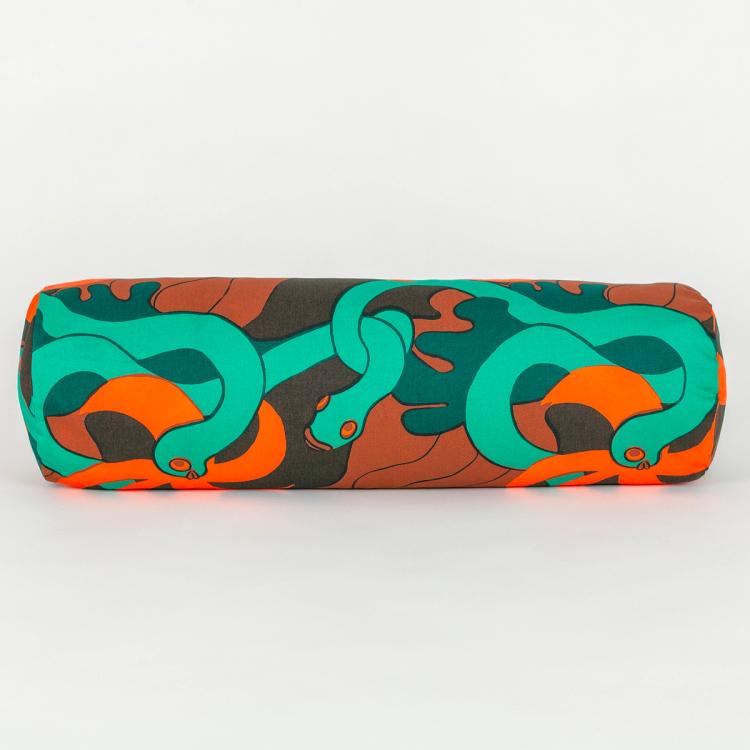A long cylindrical pillow made of fabric featuring a repeating textile pattern with stylized green snakes intertwined with abstract brown shapes and bright orange spirals on a dark brown background.
