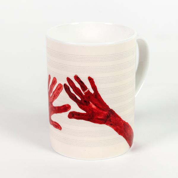 A tall cream colored mug featuring two painted red hands with fingers outstretched. The hand on the left is barely visible, its fingers just stretching into view. The hand on the right is darker and has a ring on its ring finger.