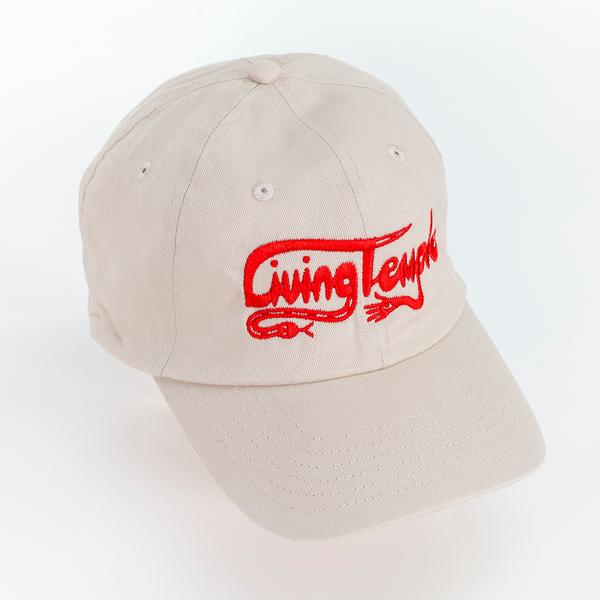A photograph of a tan baseball cap with scripted text reading "Living Temple" embroidered on the front in red thread