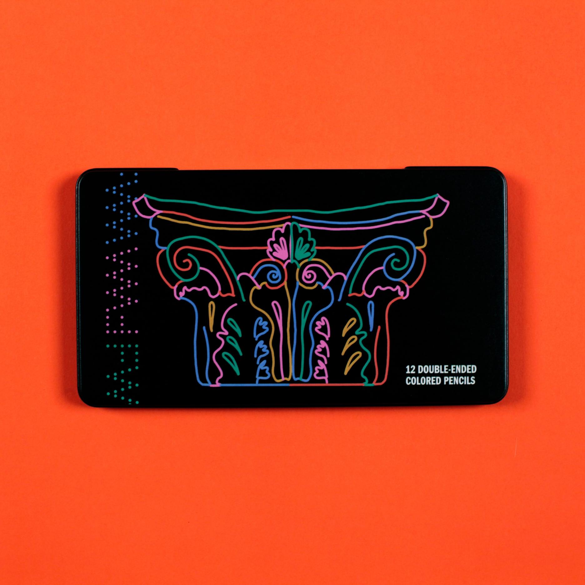 A black pencil case sits against a bright tomato red orange background. Its cover features a colorful line drawing of a corinthian column. The text reads: "12 double-ended colored pencils"