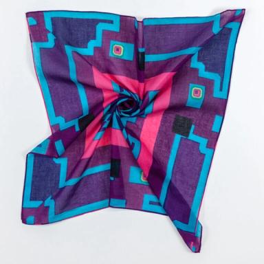A square scarf twisted in the middle, pulling its edges inward. The scarf is mostly purple, with varying shades of blue and a bright pink border around the designs in the center.