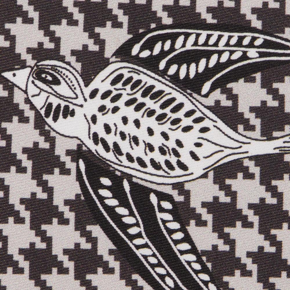 A detail of a black and white illustrated Shomoro bird flying on a light gray and black houndstooth background.