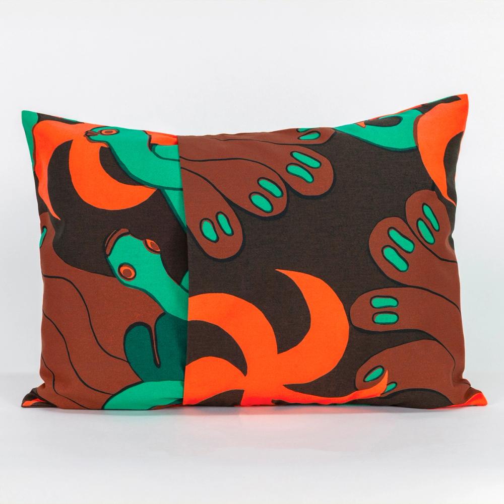 A wide rectangle-shaped pillow made of fabric featuring a repeating textile pattern with stylized green snakes intertwined with abstract brown shapes and bright orange spirals on a dark brown background. The left and right panels of fabric overlap in the center to create an opening.