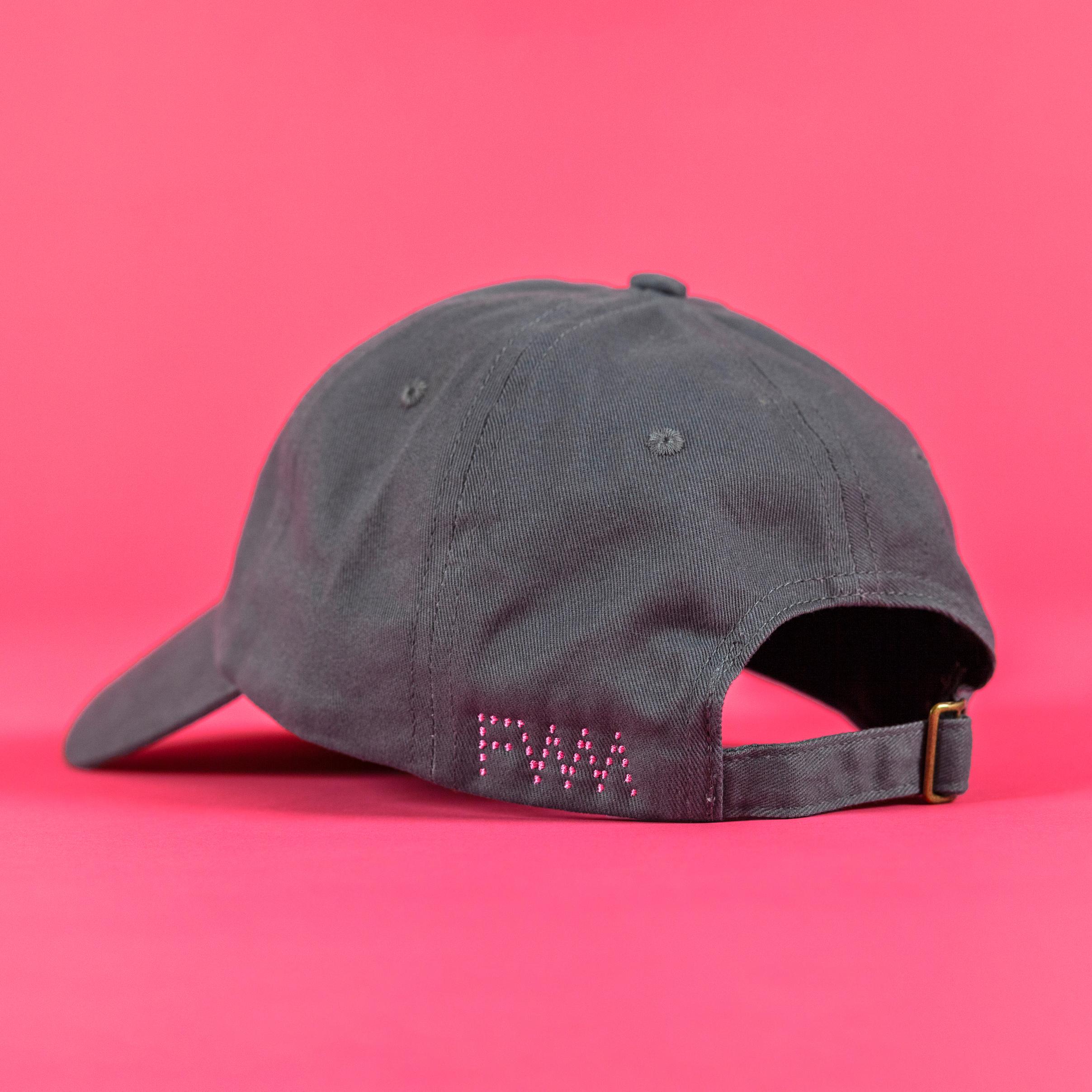 The grey baseball cap is against a bright pink background facing away from the camera. On the right side of the back, you can see the FWM logo embroidered in pink dots.