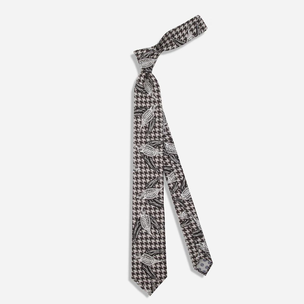 A tie with a pattern of black and white illustrated Shomoro birds flying in different directions on a light gray and black houndstooth background.
