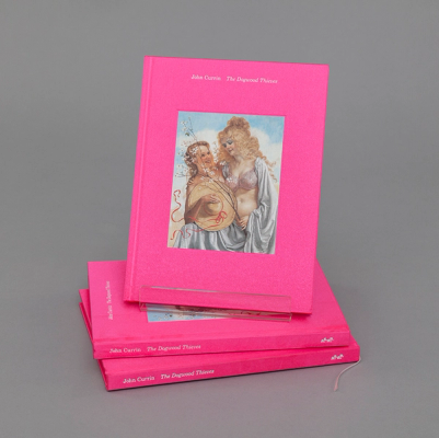 A pink book stands upright atop two other copies against a gray background. Titled "John Currin: The Dogwood Thieves," the book features a painting on its cover of two blonde women smiling and holding one another. The shorter woman on the left is holding a hat over her body, while the woman on the right is wearing a bra with a shawl over her shoulders. In her left hand, she holds a small branch with white blossoms that partially obscures her companion's face. 