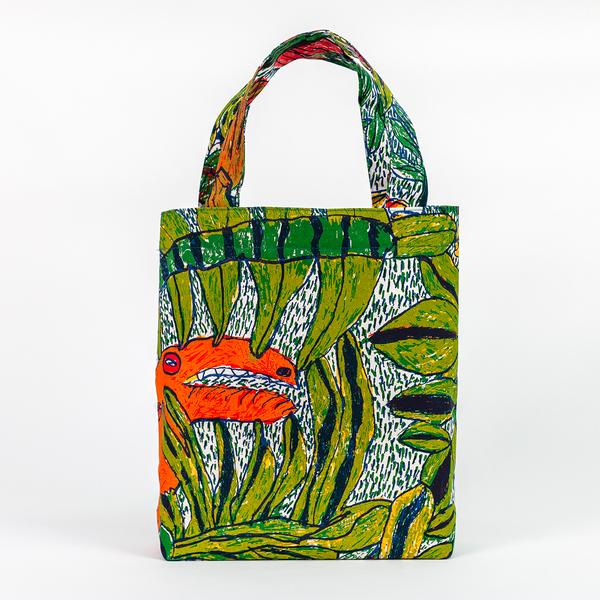 A tote bag taller than it is wide with straps about three-quarters of the bag's height. The bag features a colorful jungle scene with a tropical orange bird peering through leaves.