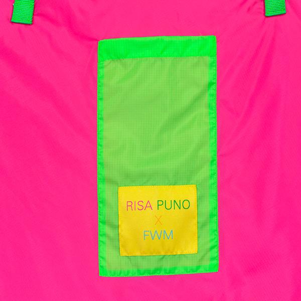 A detail of a magenta bag with a green pocket and yellow tag that reads "Risa Puno x FWM." Green straps attach to the bag near the top of the image.