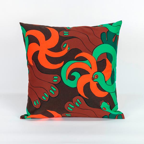 A square pillow made of fabric featuring a repeating textile pattern with stylized green snakes intertwined with abstract brown shapes and bright orange spirals on a dark brown background.