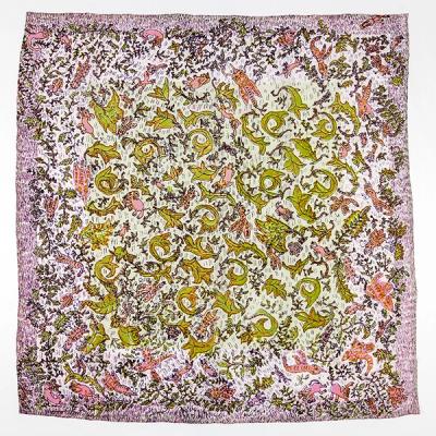 A square-shaped scarf with lots of tiny details of creatures and floral shapes. The outermost edges of the scarf are a mauve with the innermost part of the scarf a lighter pink with green and bright pink details.