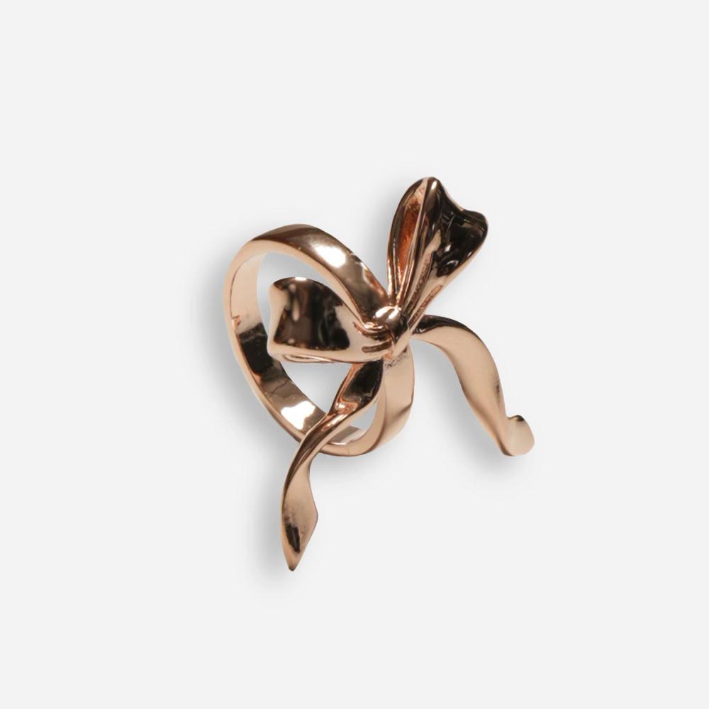 A rose gold colored scarf clip composed of a ring with a decorative bow on the front.