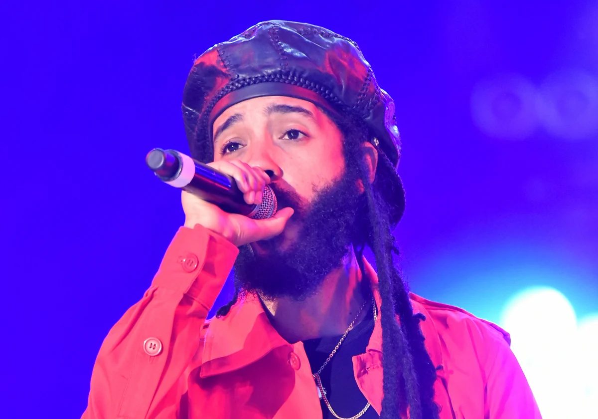 Protoje performing at Ruhr Reggae Summer in a red jacket and black cap