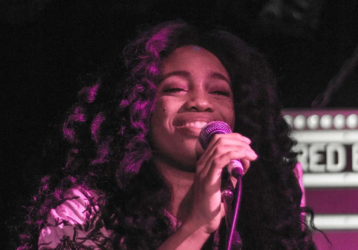 SZA smiling while performing with a microphone in Toronto