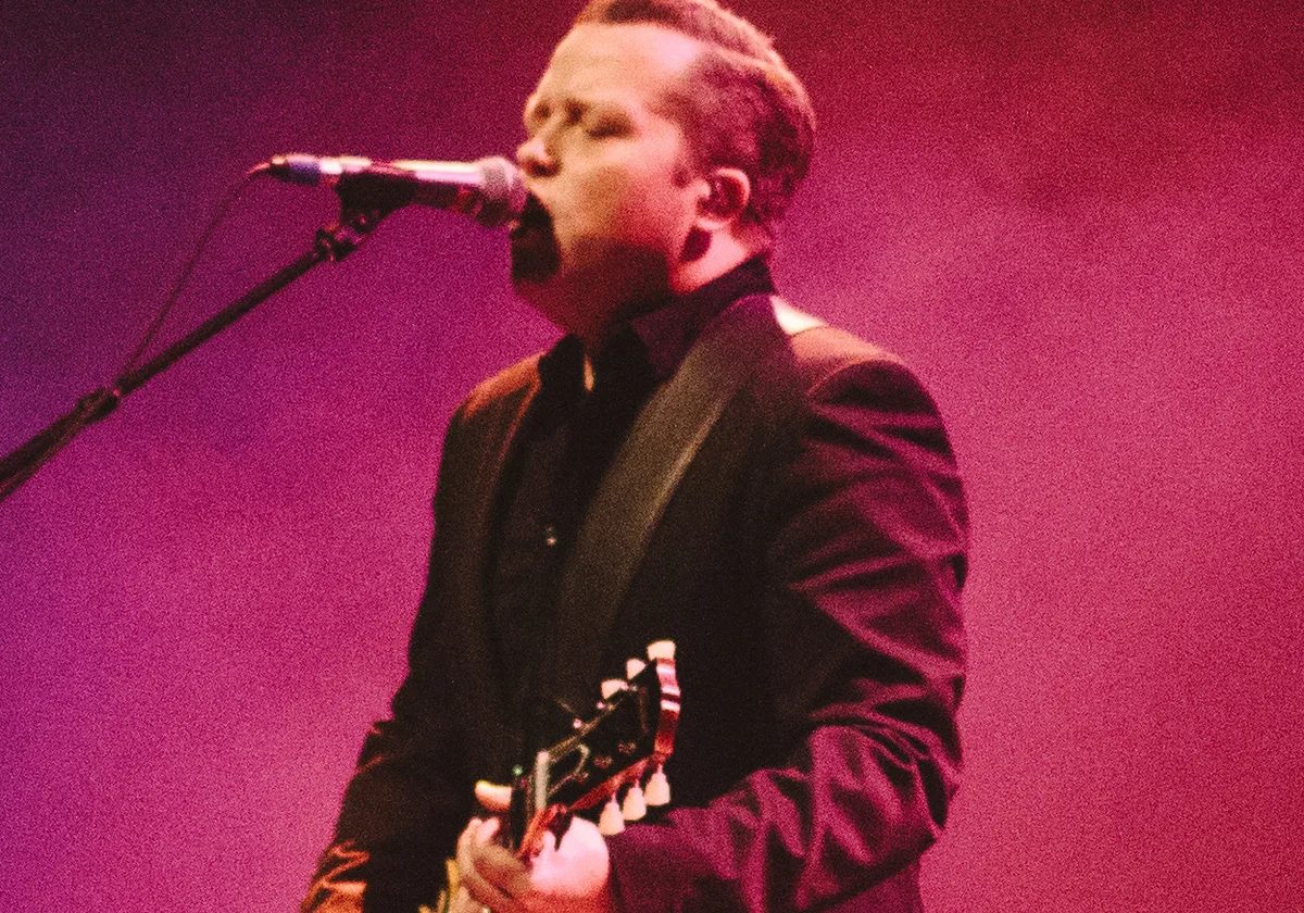 Jason Isbell singing into a microphone while playing guitar