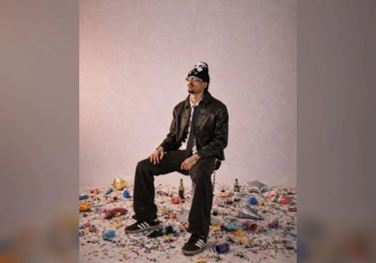 KOLA seated in a studio portrait surrounded by colourful props
