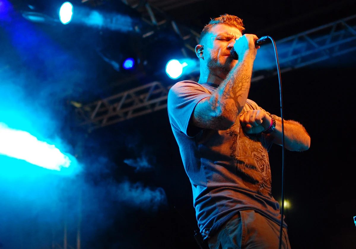 Dub FX performing live under blue stage lights with a handheld microphone