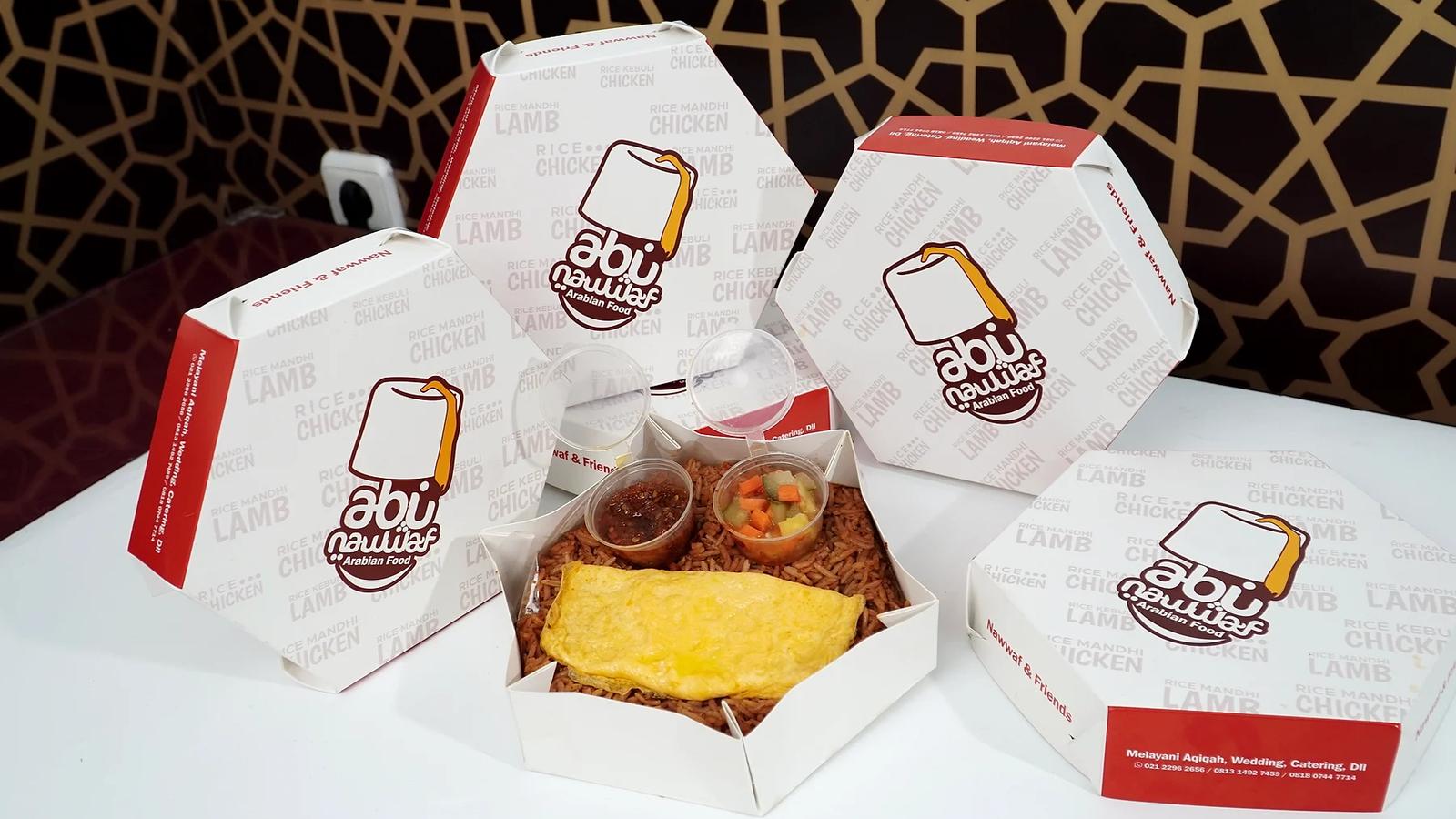 Nasi box hexagon Abu Nawwaf terbuka berisi nasi dengan omelet, sambal, dan acar, dikelilingi kotak-kotak bertuliskan Nawwaf & Friends di atas meja putih