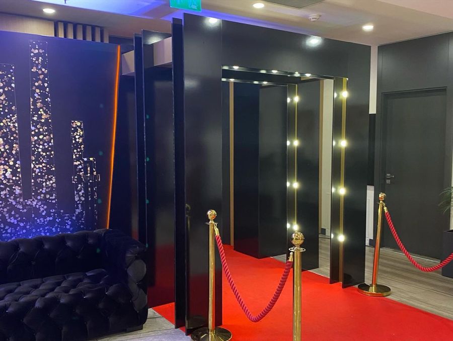 Black entrance portal lined with bulb lights, with a red carpet and gold rope barriers, at Tüpraş's new-year celebration - BACKSTAGE Event production