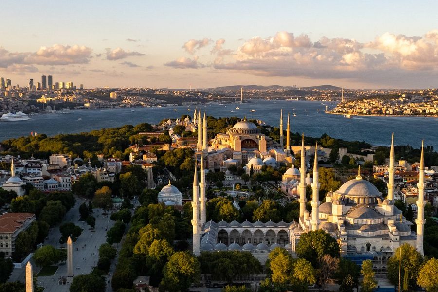 Luftaufnahme der historischen Halbinsel von Istanbul bei Abendlicht mit Hagia Sophia und Blauer Moschee, dahinter der Bosporus und die moderne Skyline