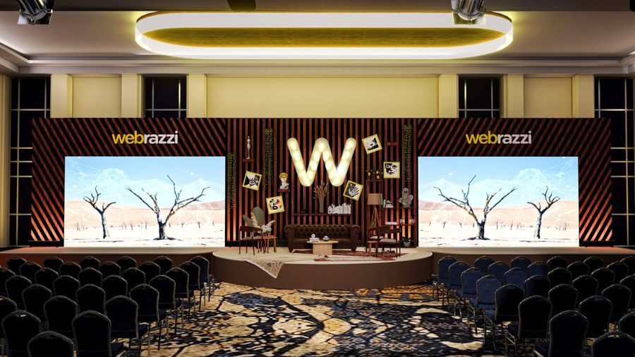 Open-air stage with a lit garland canopy over rows of seating — BACKSTAGE Event design visualisation for an outdoor evening event (design image, not a photograph)
