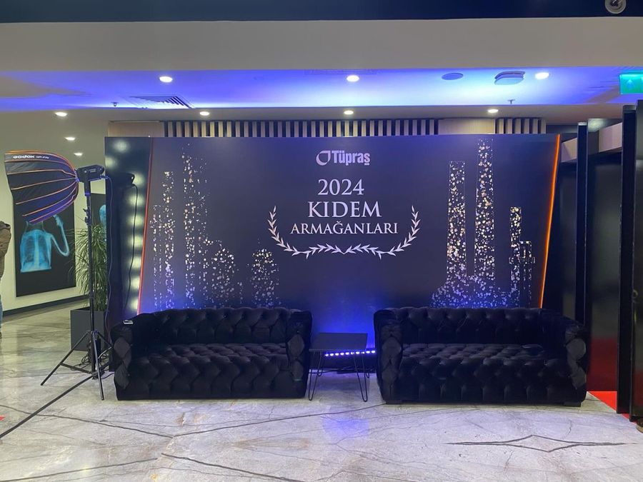 Long-service awards backdrop reading "2024 Kıdem Armağanları" with black tufted sofas at Tüpraş's new-year celebration - BACKSTAGE Event production