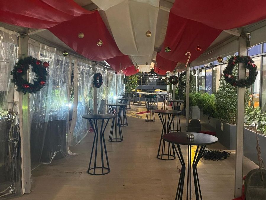 Cocktail area with high standing tables under a red and white draped ceiling, enclosed by clear side panels and hung with wreaths, at Tüpraş's new-year celebration - BACKSTAGE Event production
