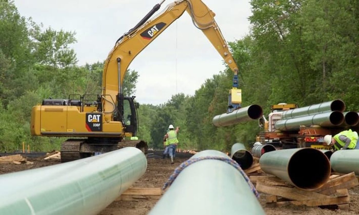 Excavators lowering sections of 24-inch steel pipeline into the Saginaw Trail right of way