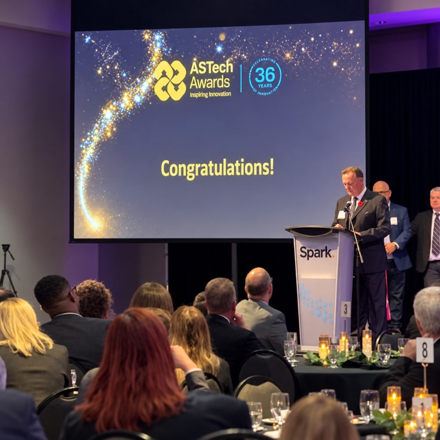 Speaker at the ASTech Awards podium with a Congratulations screen behind the stage