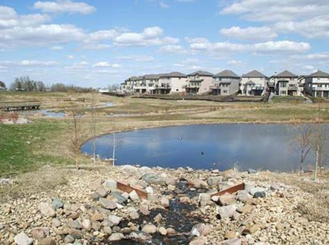 The Summerwood stormwater pond holding clear water with homes in the background