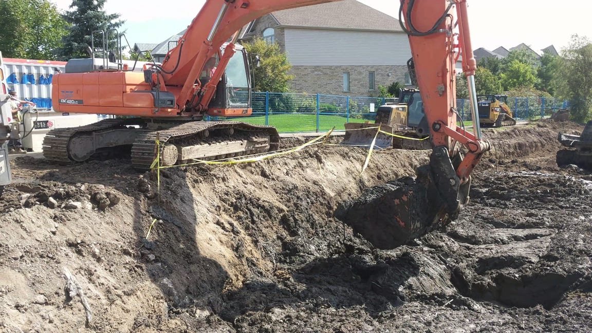 Tracked excavators digging out treated sediment from the drained pond