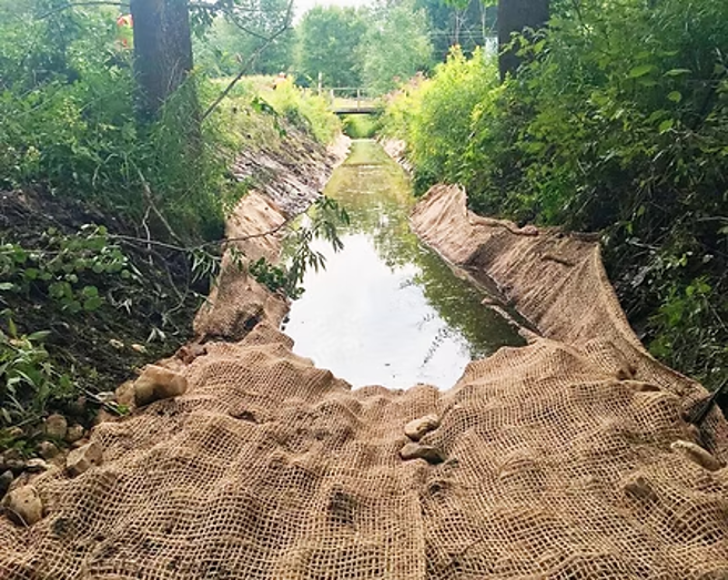 Treated silt mat lining a vegetated drainage channel