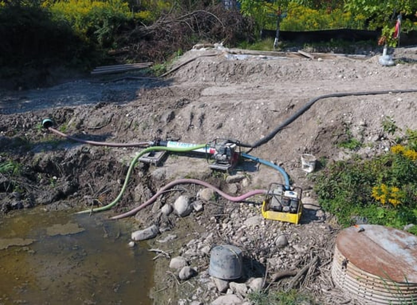 Pumps and hoses feeding a Gel Flocculant Reactor at the edge of Pond 53