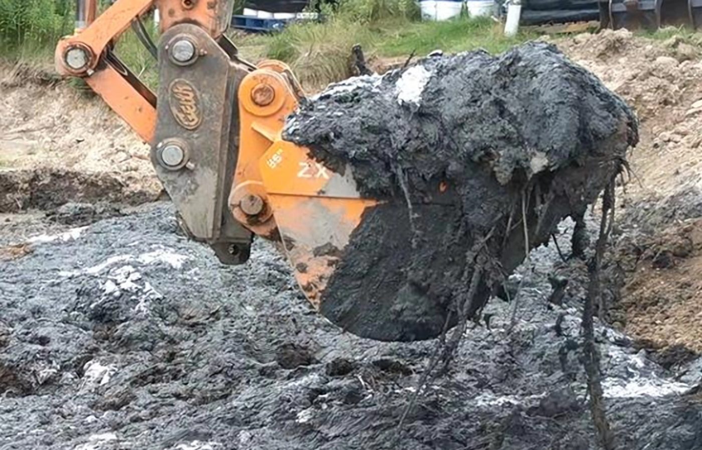 Excavator scooping solidified Ultrabind-treated material