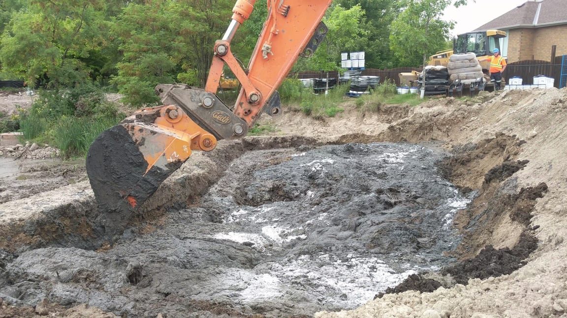 Excavator bucket lifting Ultrabind-treated sediment slurry out of Pond 53