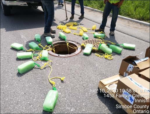 Crew laying out strings of Gel Floc blocks around an open manhole on Farrow Crescent, Innisfil