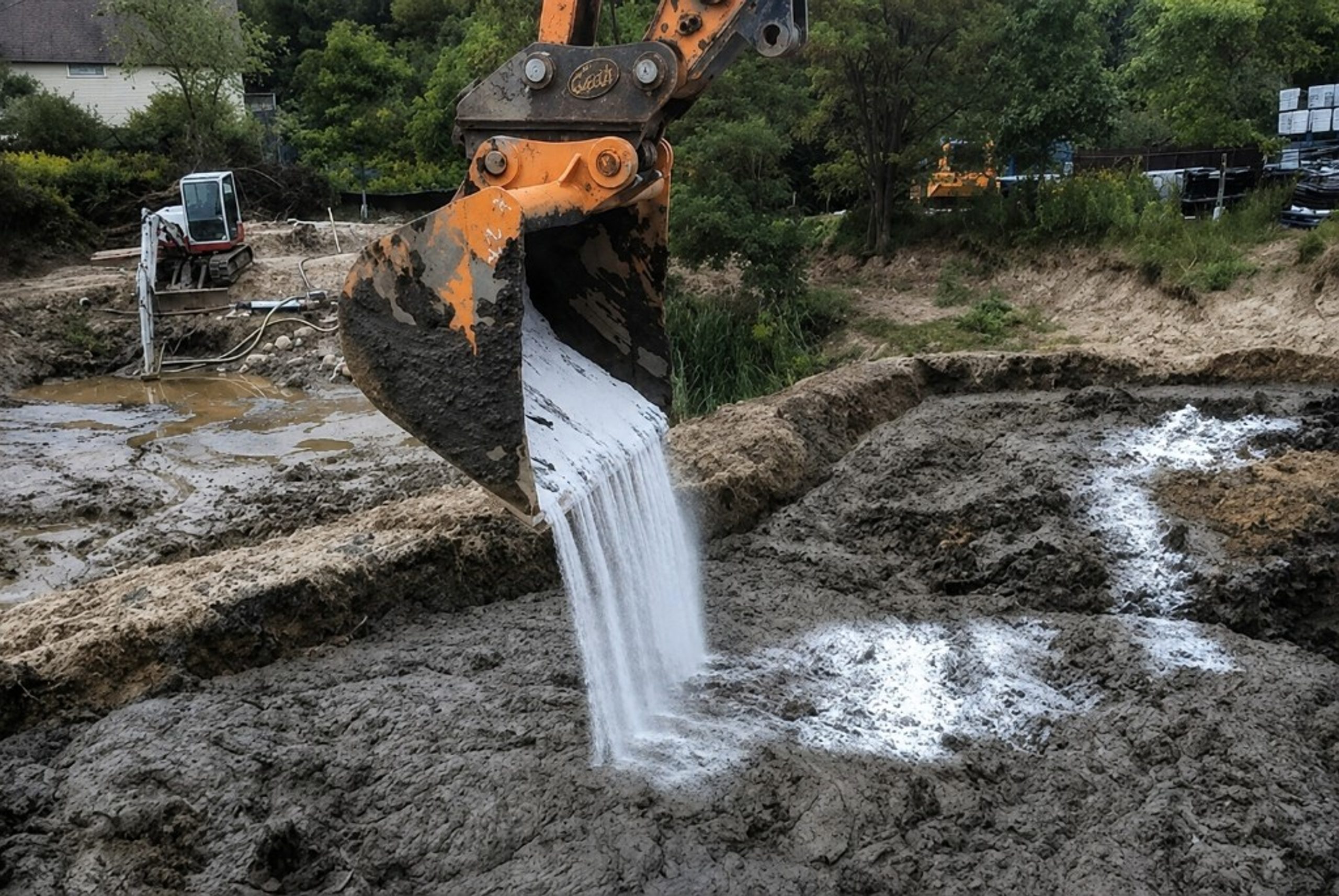 Excavator applying Ultrabind to wet soil at a construction site